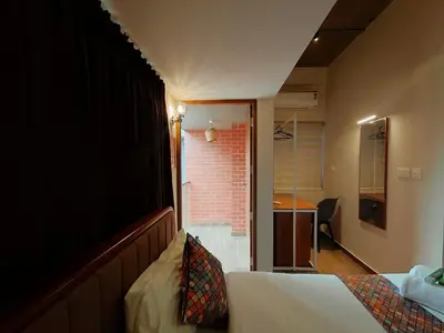a hotel room with a bed and a bathroom at Zostay Urban Retreat Deluxe Rooms & Premium Dorms in Manjeri