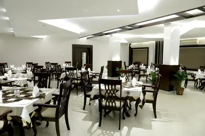 a dining room with tables and chairs with white tablecloths at Rydges Inn in Kottakkal