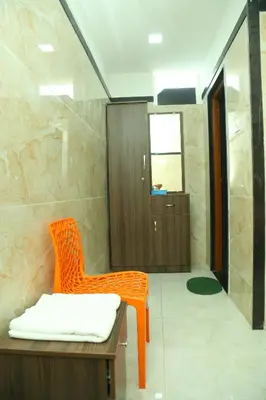 an orange chair in a bathroom with a shower at S M Residency in Tiruppūr