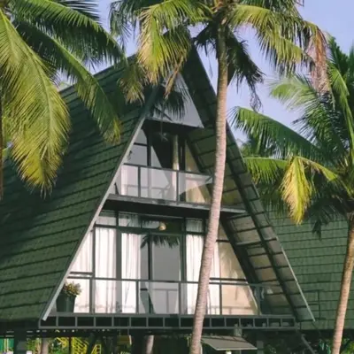 a green house with palm trees in front of it at Parlak in Karuvapadna