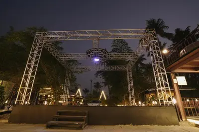 a large metal structure at night with a bench at Parlak in Karuvapadna