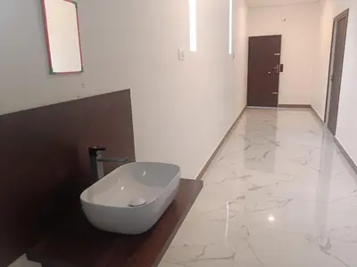 a bathroom with a white toilet on a marble floor at Riverside inn in Wayanad