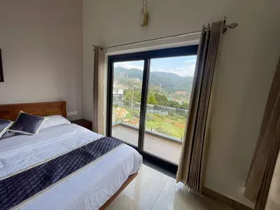 a bedroom with a bed and a large window at May Flower Cottage in Ooty