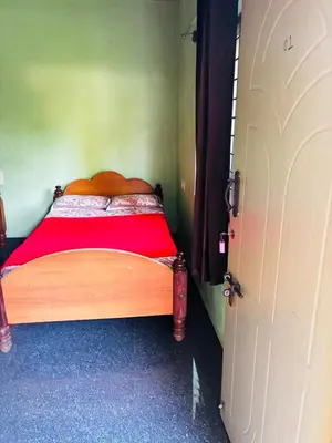 a bedroom with a wooden bed with a red blanket at Yash Residency in Mysore