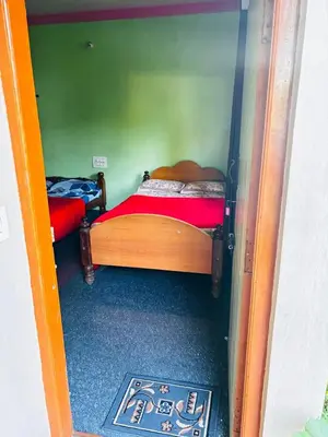 a room with two beds in a room with a door at Yash Residency in Mysore
