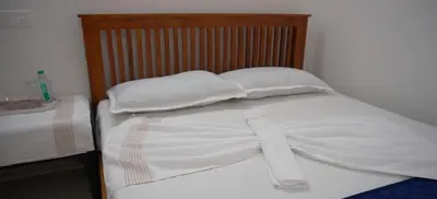 a bed with two white pillows and a wooden headboard at Smile Residency in Sultan Bathery
