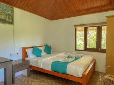 a bedroom with a bed with blue pillows and a window at The Heights Munnar in Munnar