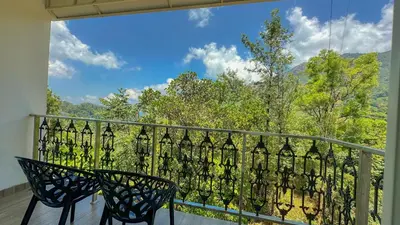 a balcony with two chairs and a view of trees at The Heights Munnar in Munnar