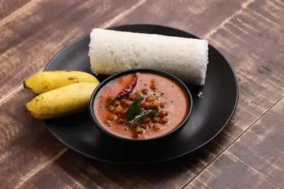 a black plate with a bowl of soup and a banana at The Heights Munnar in Munnar