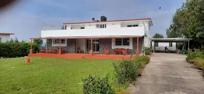 a large white house with a lawn in front of it at Mountain Top Holiday Home in Ooty