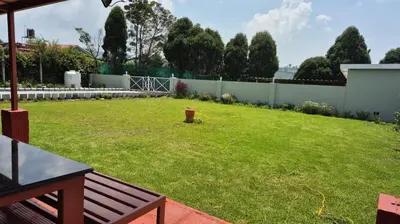 a backyard with a fence and a grass yard at Mountain Top Holiday Home in Ooty