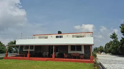 a house with chairs in front of it at Mountain Top Holiday Home in Ooty