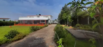 a house with a driveway in front of a yard at Mountain Top Holiday Home in Ooty