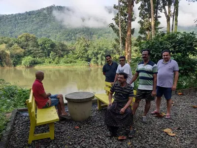 a group of men standing next to a lake at Rainy Woods Inn in Neriyamangalam