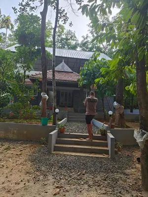 a man standing on steps in front of a house at Rainy Woods Inn in Neriyamangalam