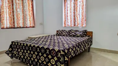 a bed in a room with two windows at Spacious 2-storey home-4 bedroom in Kunnamkulam