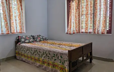 a small bed in a room with two windows at Spacious 2-storey home-4 bedroom in Kunnamkulam