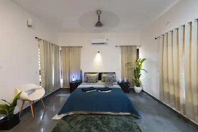 a bedroom with a blue bed and a chair in it at Verdant Courtyard, 3BHK, Near IIM, NITC in Kozhikode