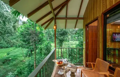 a porch with a table and chairs on a balcony at De Spicewoods, AC Cabin, Pool, Couple only in Kalpetta