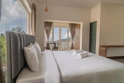 a bedroom with a white bed with a large window at The Misty Meadows in Coonoor
