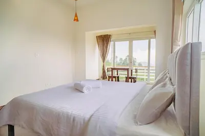 a white bed in a room with a window at The Misty Meadows in Coonoor