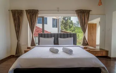 a bedroom with a large bed with two towels on it at The Misty Meadows in Coonoor