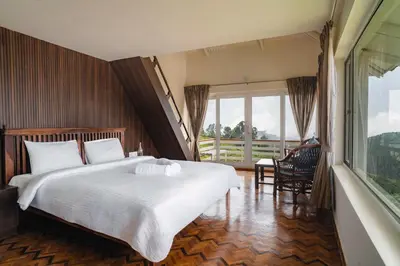 a bedroom with a large bed and a large window at The Misty Meadows in Coonoor