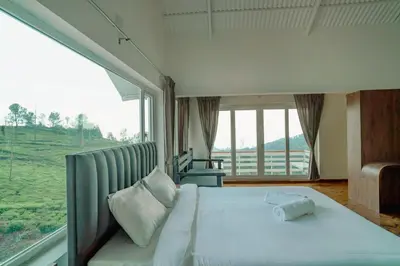 a bedroom with a large bed with a large window at The Misty Meadows in Coonoor