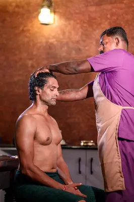 a man cutting another mans hair in a barber shop at Dr Indulekhas Ayurvedic Wellness And Rejuvenation in Tellicherry