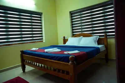 a bedroom with a bed and two windows with blinds at Sree Nandhavanam Homestay in Guruvāyūr