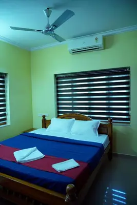 a bedroom with a bed with a ceiling fan at Sree Nandhavanam Homestay in Guruvāyūr