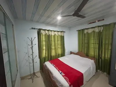 a bedroom with a bed with green curtains and a fan at Rifa homestay in Kalpetta