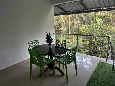 a black table and four chairs on a balcony at Rifa homestay in Kalpetta