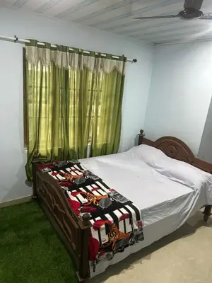 a bedroom with a bed with a green curtain at Rifa homestay in Kalpetta