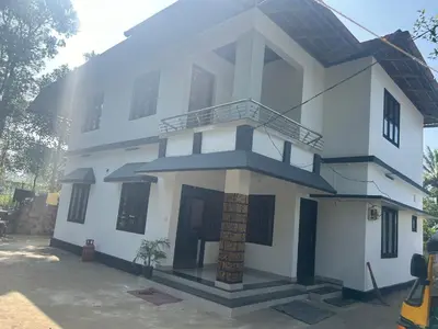 a white house with a staircase in front of it at Rifa homestay in Kalpetta
