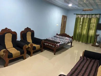 a living room with two chairs and a bed at Rifa homestay in Kalpetta