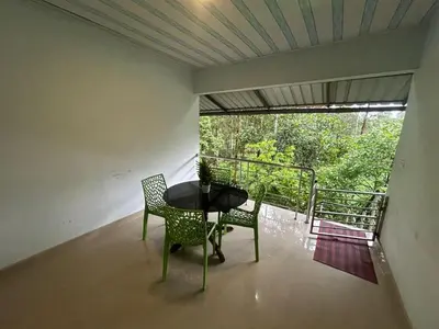 a room with a table and two chairs and a balcony at Rifa homestay in Kalpetta