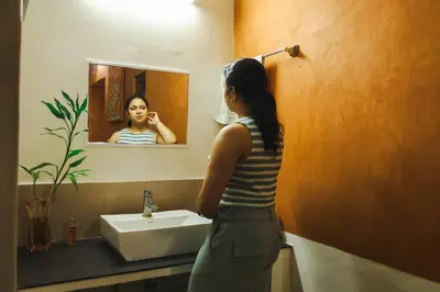a woman standing in front of a sink in a bathroom at Namastay - Haritha Thara in Kalpetta