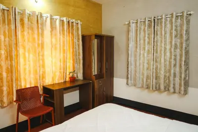 a bedroom with a bed and a desk and a chair at Namastay - Haritha Thara in Kalpetta