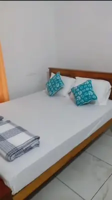 a bed with blue and white pillows on it at Peaceful Homestay near Kizhunna Beach in Thottada