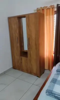 a wooden cabinet with a mirror in a bedroom at Peaceful Homestay near Kizhunna Beach in Thottada