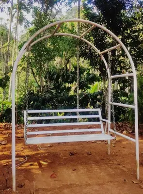 a white bench sitting under an arch in a park at Fogland Villa in Vaduvanchal