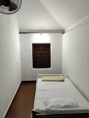 a small white room with a bed and a window at Ophel Homestay, 7 Bed Heritage Home in Mananthavady
