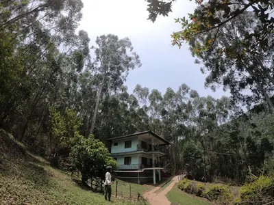 a man standing in front of a house in the forest at Sahari Villa, Vattavada in Vattavada
