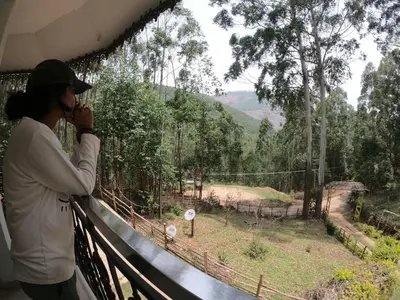 a woman standing on a balcony taking a picture of a zoo at Sahari Villa, Vattavada in Vattavada