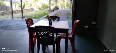 a table with four chairs and a table and a table and chairsearcher at Hidden Haven 1BR Coorg in Kushālnagar