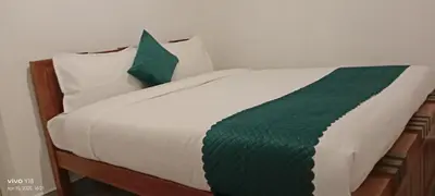 a white bed with green and white sheets and pillows at Hills Dale ooty 3 bhk vintage tea estate villa in Ooty