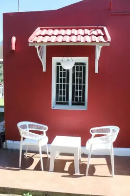 two chairs and a table in front of a red building at Hills Dale ooty 3 bhk vintage tea estate villa in Ooty