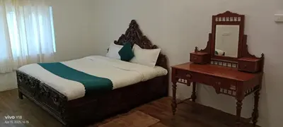 a bedroom with a bed and a table with a mirror at Hills Dale ooty 3 bhk vintage tea estate villa in Ooty
