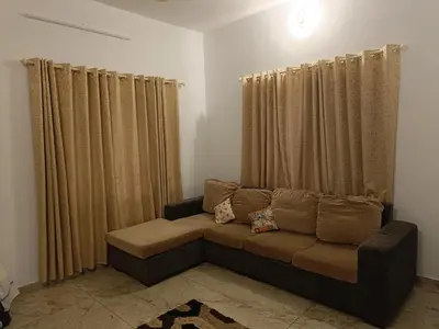 a couch sitting in a living room with curtains at La casona in Kottayam